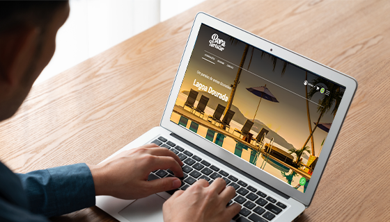 na imagem, vemos um homem com seu notebook aberto. na tela, um site de uma loja de turismo dentro sistema de reservas para passeios Tourbinou.