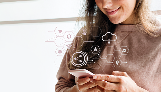 na imagem, vemos uma moça usando seu celular onde aparecem alguns símbolos que remetam a tecnologias, como armazenamento em nuvem, um elemento fundamental para digitalizar empresas de turismo.