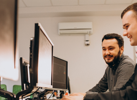 na imagem, vemos dois homens trabalhando em seus computadores.