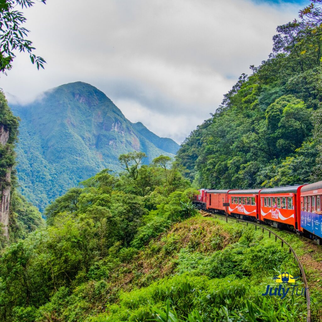 na imagem, vemos um trem da cor vermelha passando na região de Morretes, Curitiba. o passeio é vendido na loja virtual de passeios da Julytur.