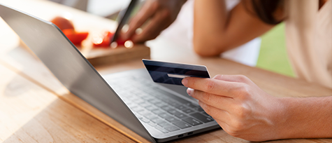 na imagem, vemos uma pessoa segurando um cartão de crédito na cor preta enquanto faz uma compra virtual. essa forma de pagamento é um sistema pagamento online mais utilizado por consumidores do mundo todo.