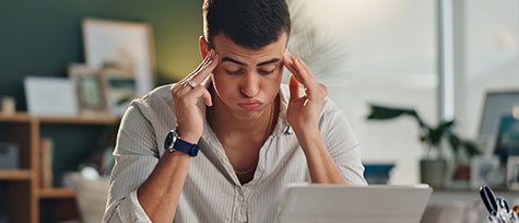 na imagem, vemos um homem com expressão de preocupação enquanto olha para o computador. a imagem ilustra o conteúdo do blog sobre como evitar taxas de cancelamento durante alta temporada no turismo.