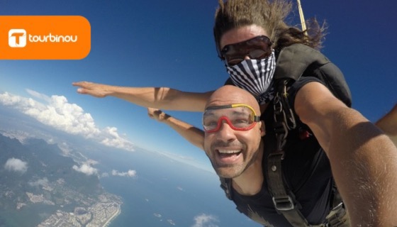na imagem, vemos dduas pessoas saltando de paraquedas. A imagem foi retirada do site da empresa No Limits Aventura, que comercializa esse tipo de atividade, que faz parte do segmento de turismo de aventura.